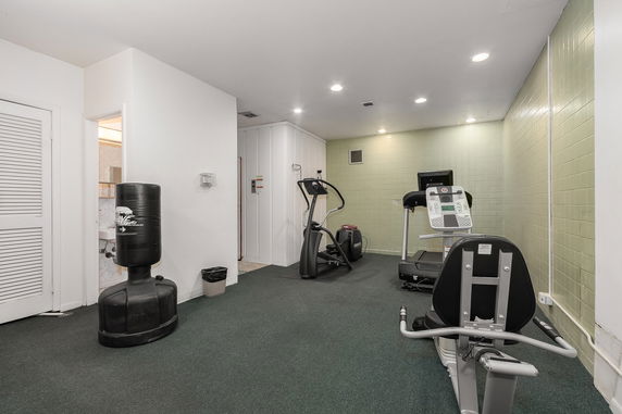 Indoor gym area with exercise equipment including a treadmill and punching bag.
