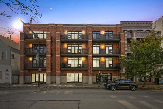 Front view of a multi-story brick apartment building with balconies.