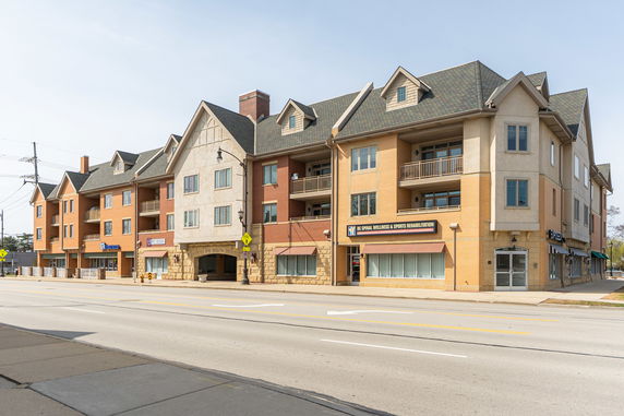Front view of a multi-story commercial and residential building with varied architectural features.