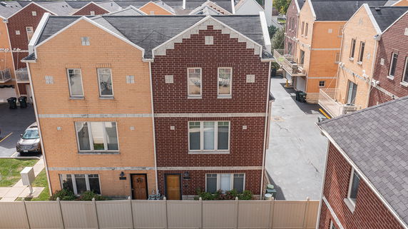 Front view of multi-story brick townhouses with contrasting colors and multiple windows.