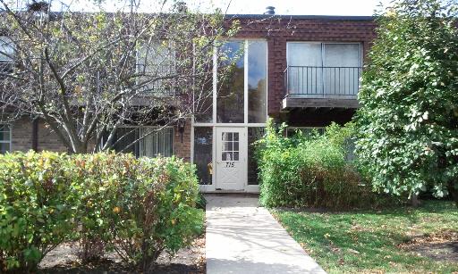 Front view of a two-story brick house with a glass entrance and a small balcony.