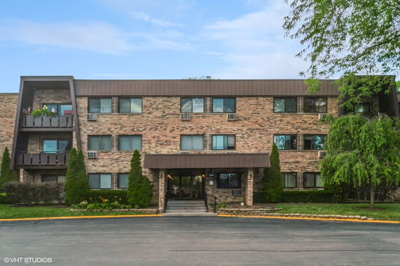 Front view of a three-story brick apartment building with balconies.