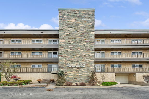 Front view of a multi-story residential building with stone accents and balconies.