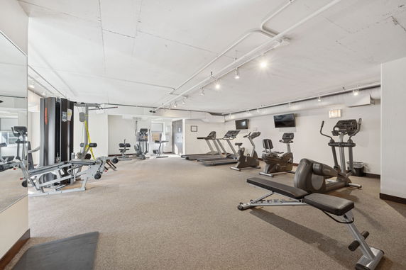 Indoor gym area with exercise equipment including treadmills, elliptical machines, and weight machines.