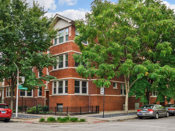 Front view of a brick apartment building with multiple floors and large windows.