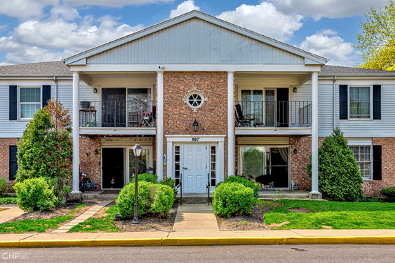 Front view of a two-story building with brick and siding exterior, featuring balconies and a central entrance.
