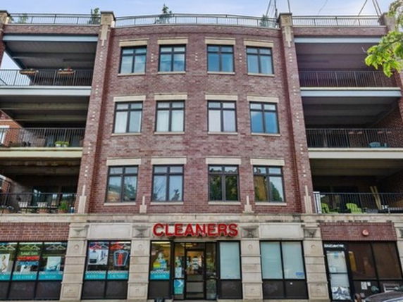 Front view of a multi-story brick building with a dry cleaners on the ground floor.