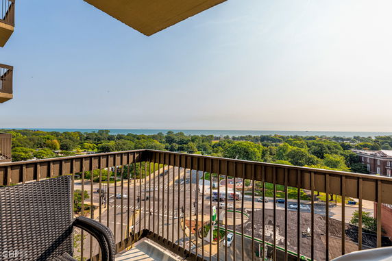 View from a balcony overlooking a scenic landscape with trees and distant water.