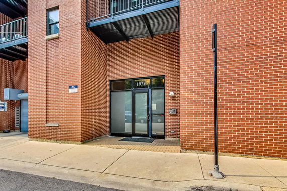 Front view of a brick building entrance with a glass door and overhang.