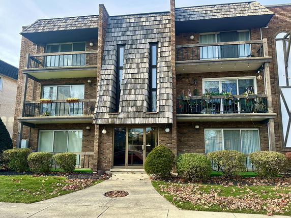 Front view of a three-story building with balconies and a brick facade.
