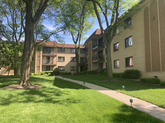 Front view of a multi-story brick apartment building with balconies.