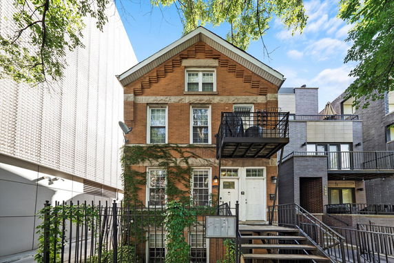 Front view of a two-story brick house with a balcony and staircase.