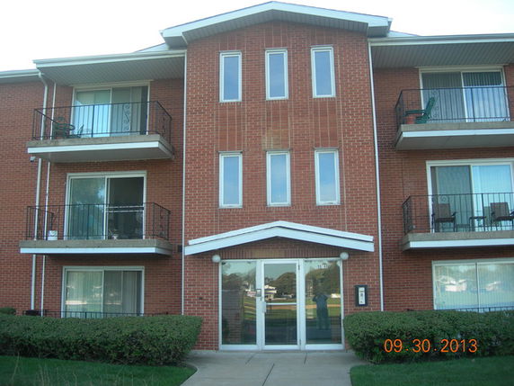 Front view of a multi-story brick apartment building with balconies.