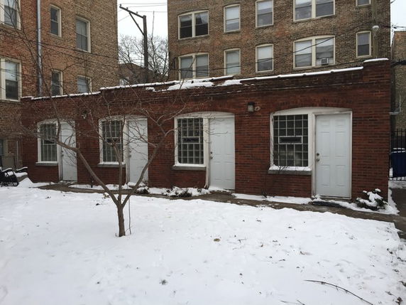 Front view of a brick building with multiple doors and windows.