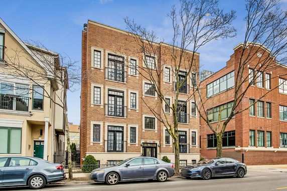 Front view of a multi-story brick apartment building with large windows and metal railings.