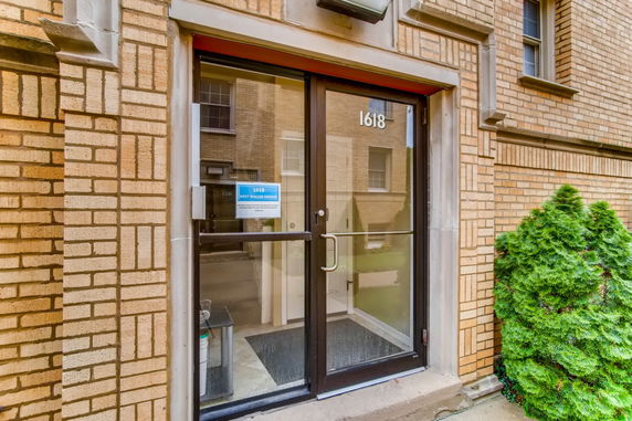 Front view of a brick building entrance with a glass door.