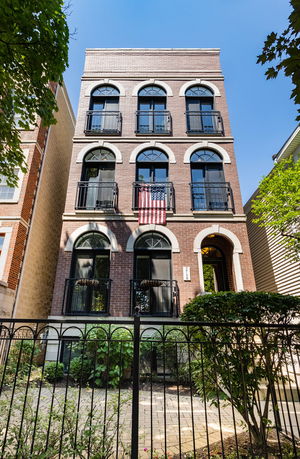 Front view of a multi-story brick building with arched windows and a balcony.
