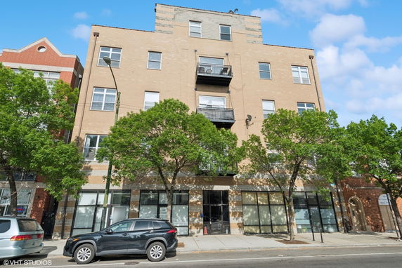 Front view of a multi-story brick building with balconies on upper floors.