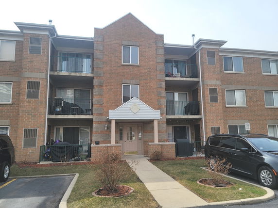 Front view of a three-story apartment building with brick exterior and balconies.