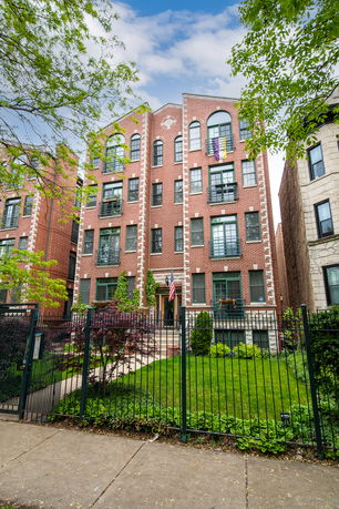 Front view of a multi-story brick building with a gated entrance.