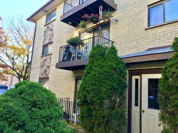 Front view of a multi-story apartment building with balconies and brick exterior.