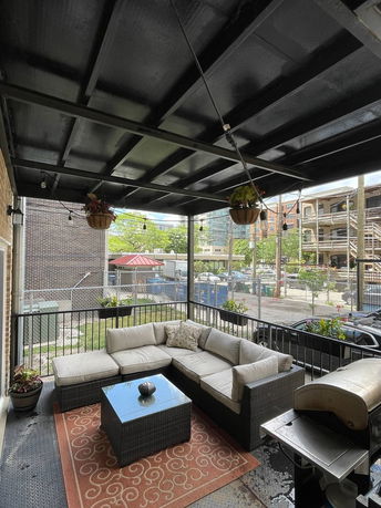 Covered outdoor patio with seating area and grill.