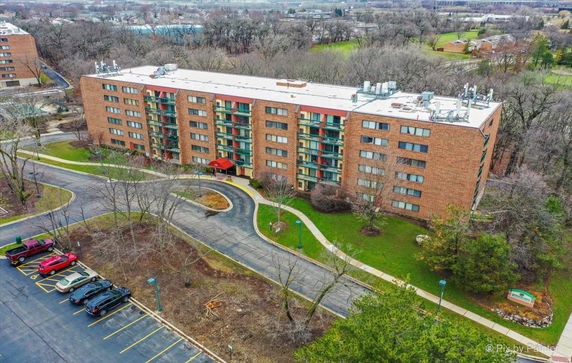 Front view of a multi-story apartment building with a curved driveway and parking area.