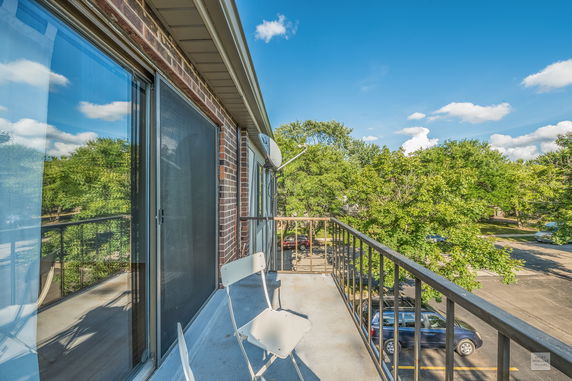 View from a balcony overlooking trees and a parking area.