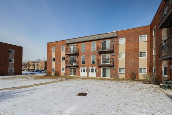 Front view of a multi-story brick apartment building with balconies.