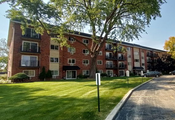 Front view of a four-story brick apartment building with balconies.