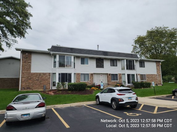 Front view of a two-story residential building with parking area.