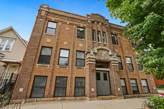 Front view of a three-story brick building with multiple windows.