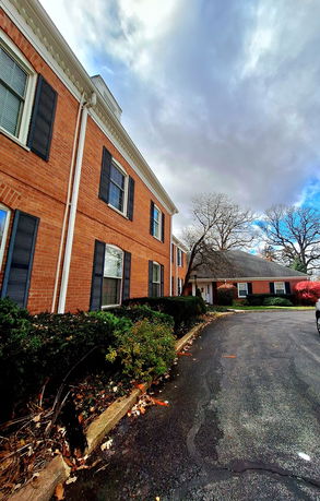 Front view of a two-story brick building with multiple windows and a paved driveway.