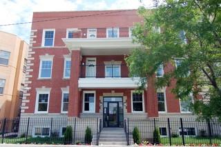 Front view of a three-story brick apartment building with balconies.