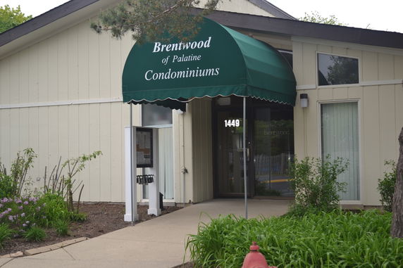 Front view of a condominium building with a green awning entrance.