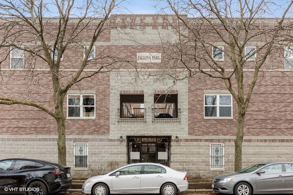 Front view of a brick multi-story building with rectangular windows and a central entrance.