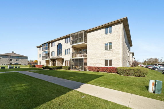Front view of a multi-story apartment building with brick exterior and balconies.