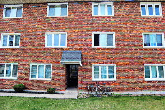 Front view of a multi-story brick building with multiple windows.