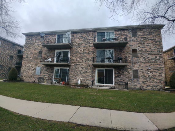 Front view of a multi-story brick apartment building with balconies.