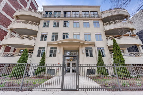Front view of a multi-story building with balconies and gated entrance.