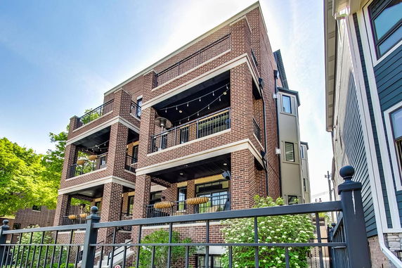 Front view of a multi-story brick building with balconies and decorative lighting.