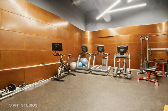 Indoor gym area with exercise equipment including treadmills, a stationary bike, and weight machines.
