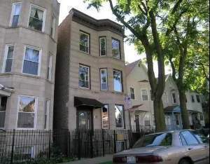 Front view of a multi-story residential building with large windows and an entrance canopy.