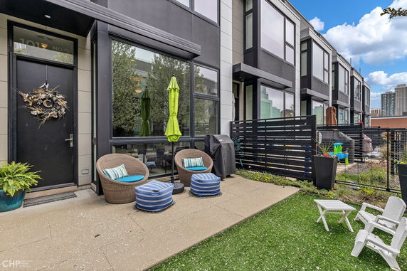 Front view of a modern townhouse with patio area and seating.
