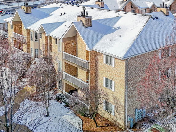 Front view of a multi-story apartment building with balconies and snow-covered roof.