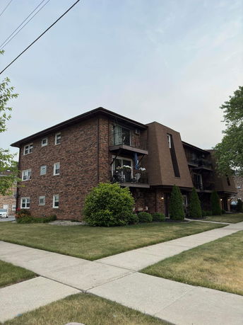 Front view of a brick apartment building with balconies.