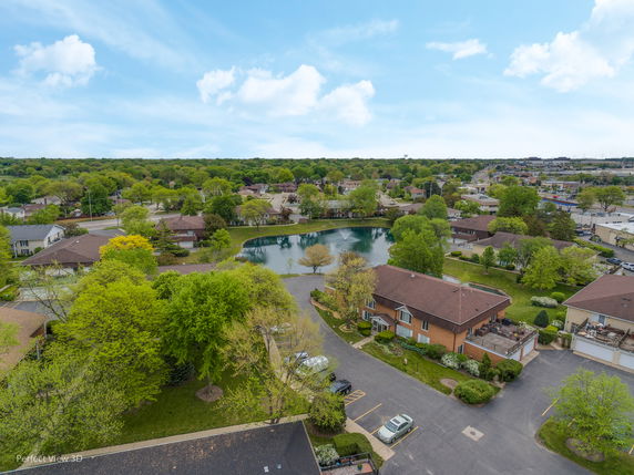 Panoramic view of a residential neighborhood with houses and a small lake.