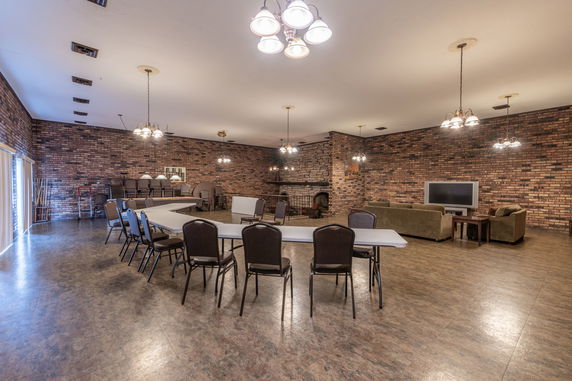 Interior of a spacious room with tables, chairs, and seating area with a television.