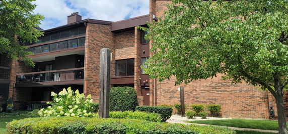 Front view of a multi-story brick apartment building with balconies.