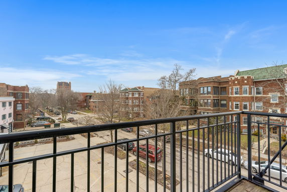 View from a balcony showing nearby residential buildings and a street.